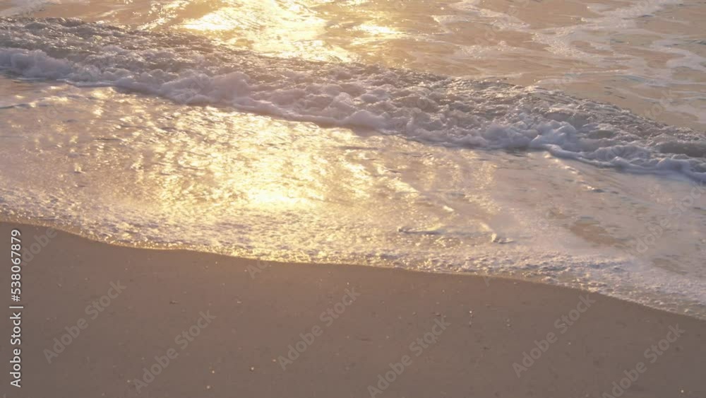 the waves and sand are illuminated golden by the sunset, slowmotion the waves and sand are illuminated golden by the sunset, slowmotion