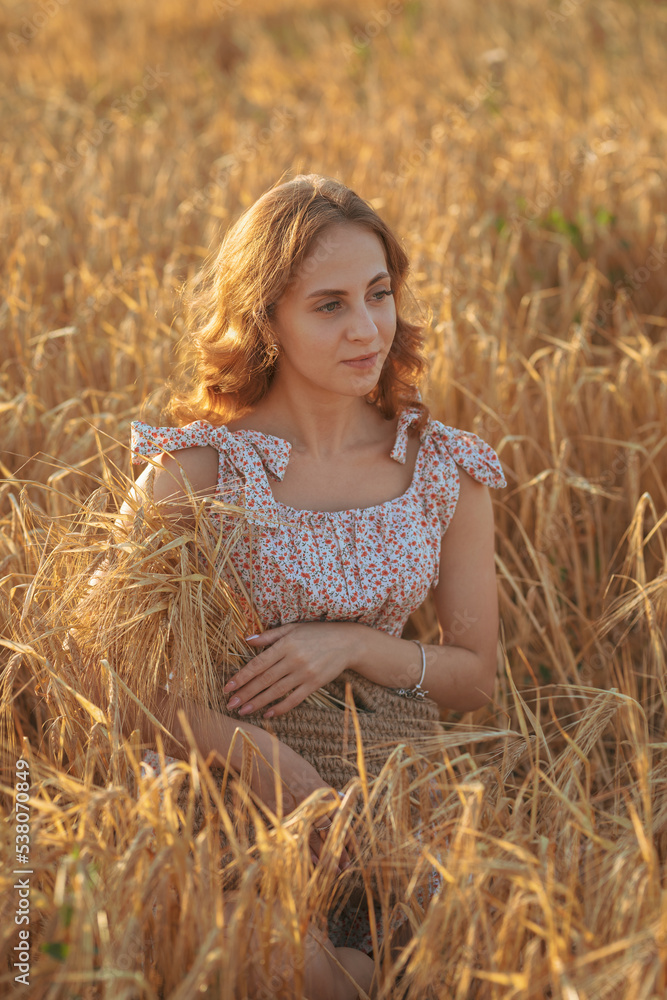 Portrait of a beautiful young woman. A woman poses in a wheat field at sunset and looks at the camera. Portrait of a beautiful young woman. A woman poses in a wheat field at sunset and looks at the camera.