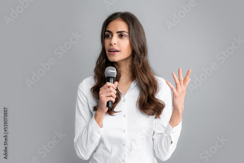 Beautiful business woman is speaking on conference. Young business woman talking with mic. Woman talking with microphone. Communication and information concept.