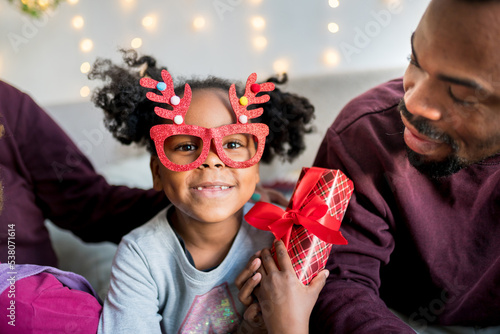 Portrait of smiling african american girl unpacking a gift box and enjoying Christmas day at home..