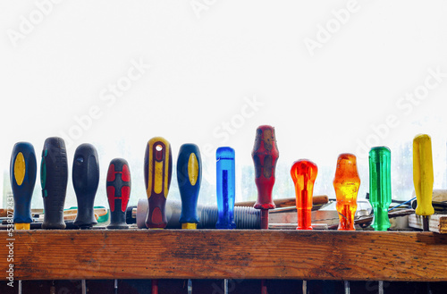 Set of old tools for repair and construction. Small and large hand tool screwdrivers hanging on wall in workshop, Tool shelf against white background. 