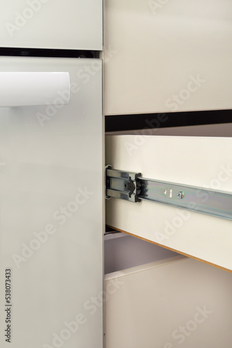 Roller stainless guide or rail for drawers with a closer. Close-up on a white background.