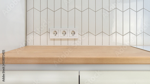 View of kitchen wood countertop and white chevron tiles. Built-in socket. Minimalistic Scandinavian design. Free empty space work surface and hob.surface.