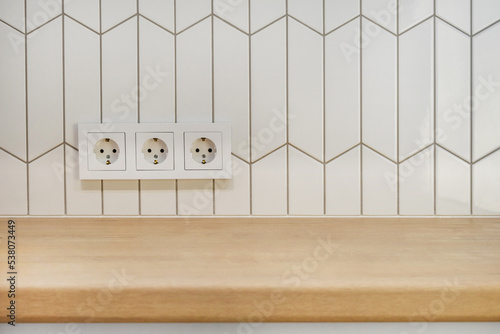 View of kitchen wood countertop and white chevron tiles. Built-in socket. Minimalistic Scandinavian design. Free empty space work surface and hob.surface.