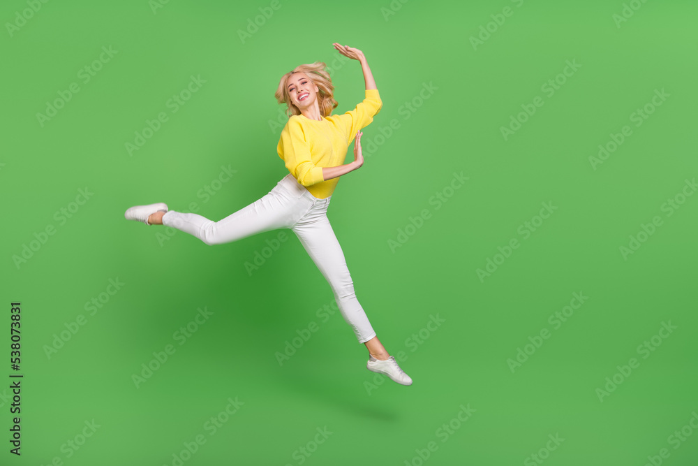 Photo of excited dreamy lady dressed yellow pullover jumping high empty space isolated green color background Photo of excited dreamy lady dressed yellow pullover jumping high empty space isolated green color background