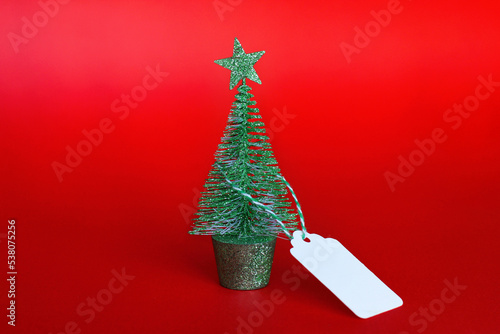 Christmas tree with a tag on a red background. the concept of Christmas sales and discounts