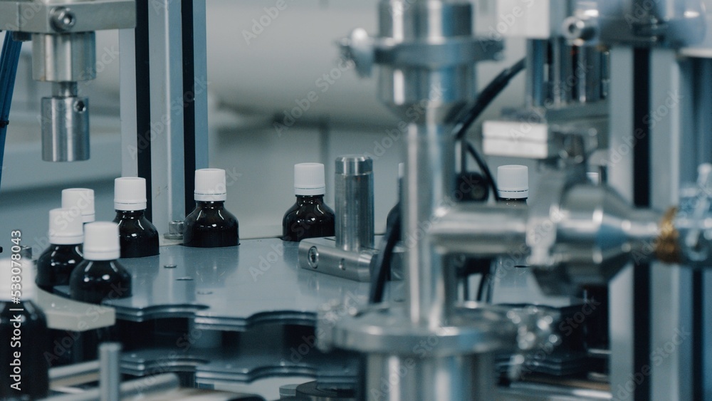 Automated production line conveyor in a factory with screw caps on glass bottles. Medical Conveyor Production of Pharmaceuticals. Twist Bottles. Pharmaceutical Industry. Close up, DOF Automated production line conveyor in a factory with screw caps on glass bottles. Medical Conveyor Production of Pharmaceuticals. Twist Bottles. Pharmaceutical Industry. Close up, DOF