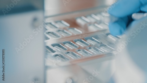Pharmacologist checks blister packs with medicinal capsules moving on a conveyor. Plastic package with capsule meds. Medication capsules in blisters. Pharmaceutical factory production line. Macro