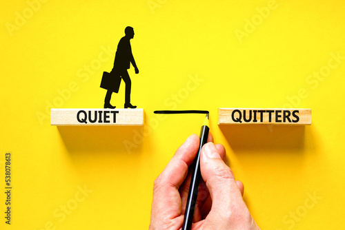 Quiet quitters symbol. Concept words Quiet quitters on wooden blocks. Beautiful yellow table yellow background. Businessman hand. Businessman icon. Business and quiet quitters concept. Copy space. photo
