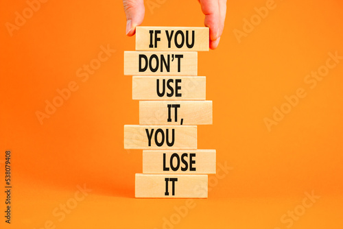 Use or lose symbol. Concept words If you do not use it you lose it on wooden blocks on a beautiful orange background. Businessman hand. Business motivational and use or lose concept.