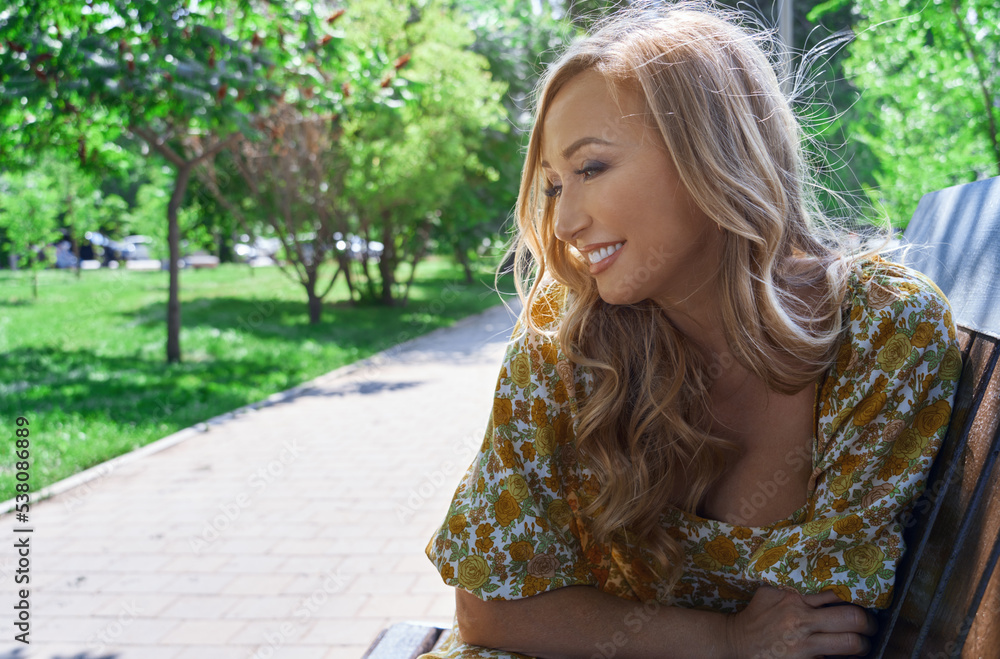 Naklejka premium Happy blond woman relaxing in a public park