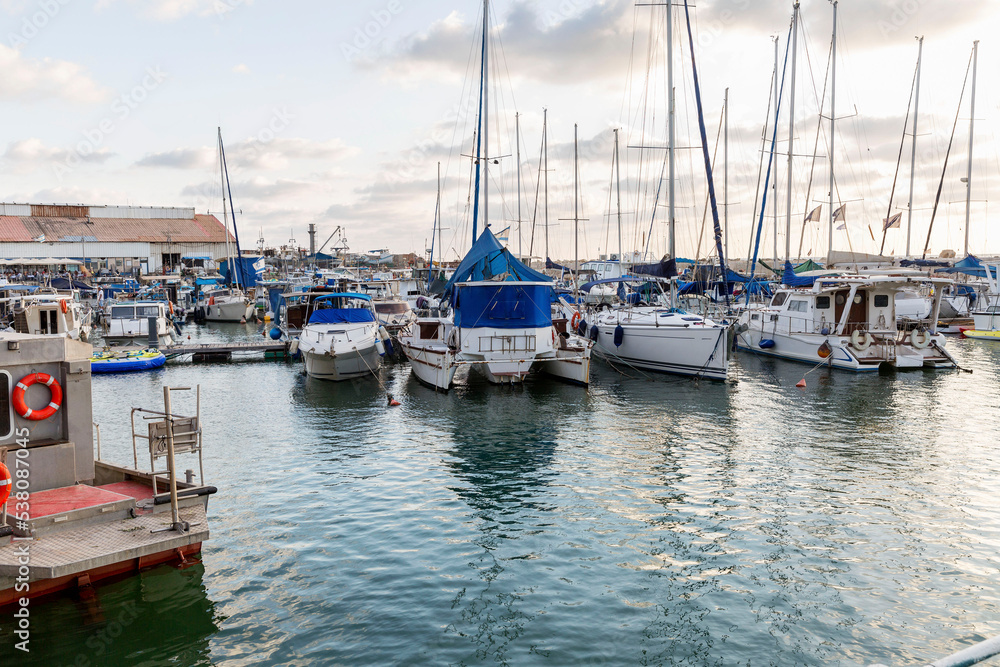 Sailing yachts and fishing boats in the marina in the evening. Romantic rest and business.