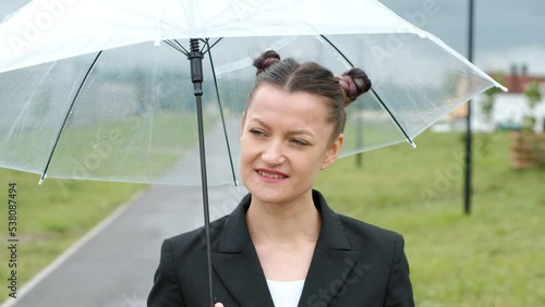 A woman in a black jacket under a transparent umbrella, on the street of the city, outdoors. Rain.