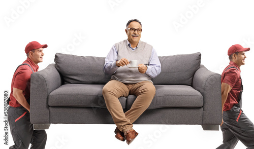 Movers carrying a couch and a mature man sitting and drinking coffee