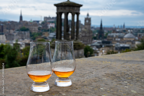 Two glasses of single malt scotch whisky and view from Calton hill to park and old parts of Edinburgh city in rainy day, Scotland, UK © barmalini