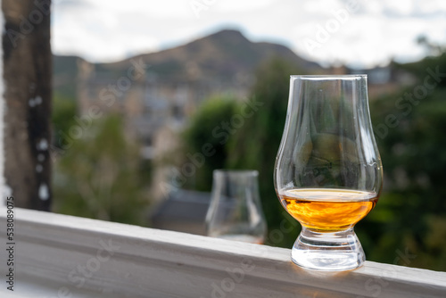 Glass of single malt scotch whisky served on old window sill in Scottisch house with view on old part of Edinburgh, Scotland, UK