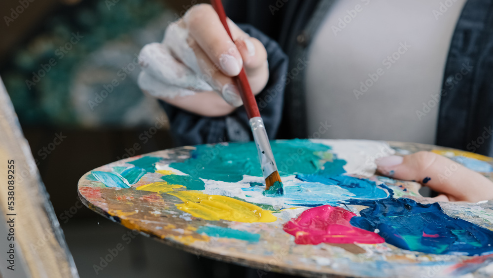Closeup woman female hand artist painter paints draws creating new art work on canvas in workshop lesson of painting enjoying process of drawing creating picture using brush applying oil paint palette Closeup woman female hand artist painter paints draws creating new art work on canvas in workshop lesson of painting enjoying process of drawing creating picture using brush applying oil paint palette