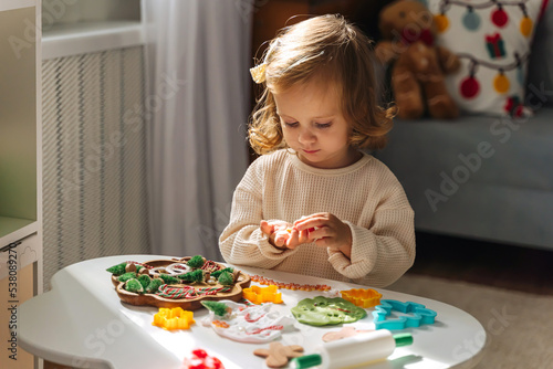 A little girl playing with play dough and Christmas decorations. Child hands creating Christmas crafts. Holiday Art Activity for Kids. Sensory play for toddlers.