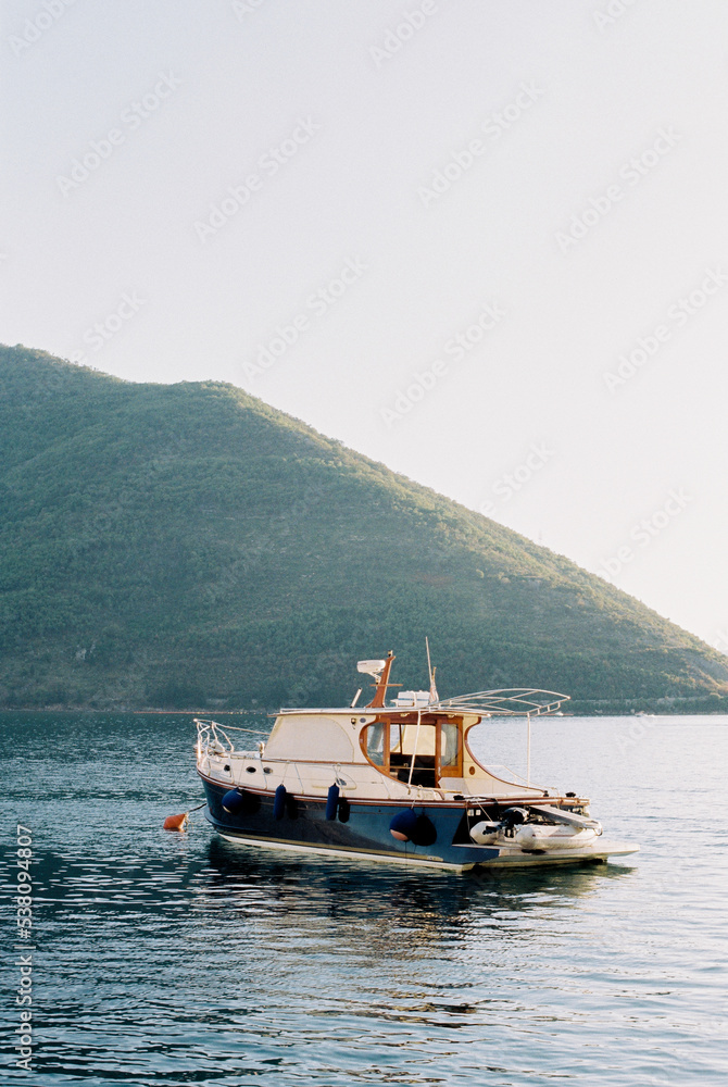 Small yacht is moored at the foot of a mountain