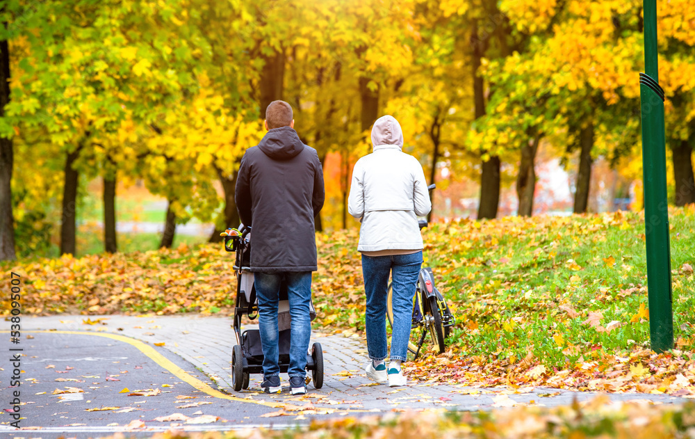 A married couple rolls a baby stroller in a city Park A married couple rolls a baby stroller in a city Park