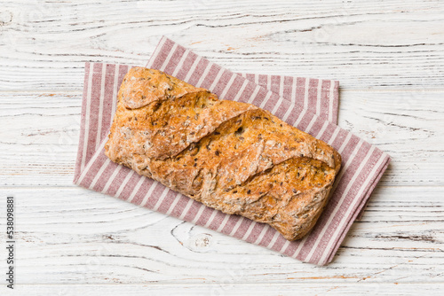 Fresh loaves of bread with wheat and gluten on a colored table. bread on napkin on rustic background, fresh bread top view