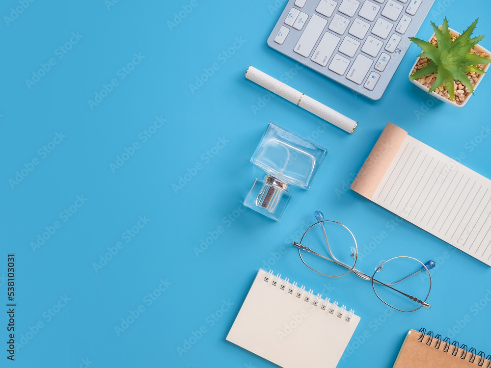 Directly above of office table desk with keyboard on blue background Directly above of office table desk with keyboard on blue background