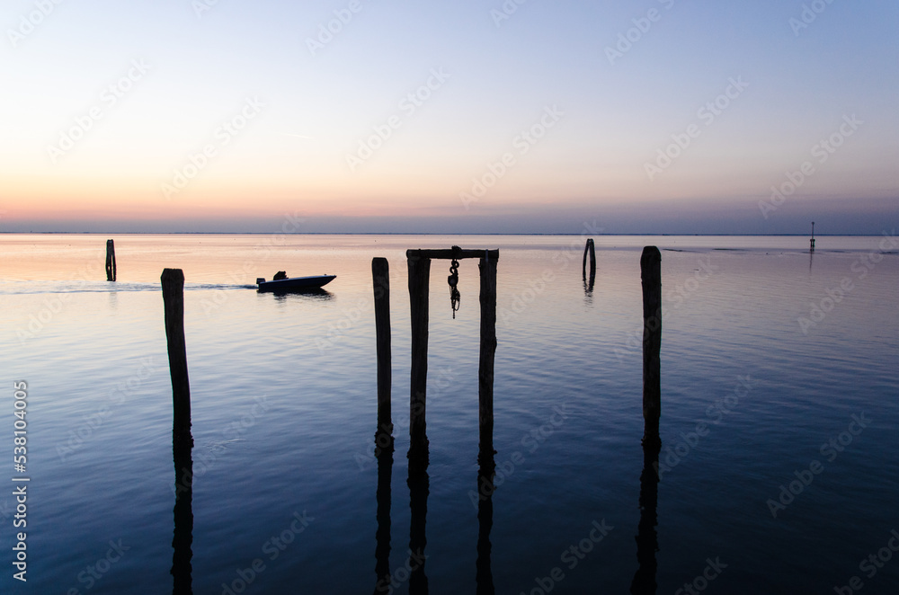 Un motoscafo naviga veloce nella laguna di Venezia, a Pellestrina, al crepudscolo