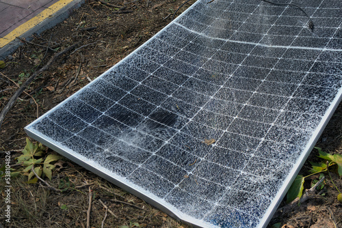 A broken solar panel, a torn panel mount lie on the ground. Consequences of a natural disaster. Green energy and natural conditions