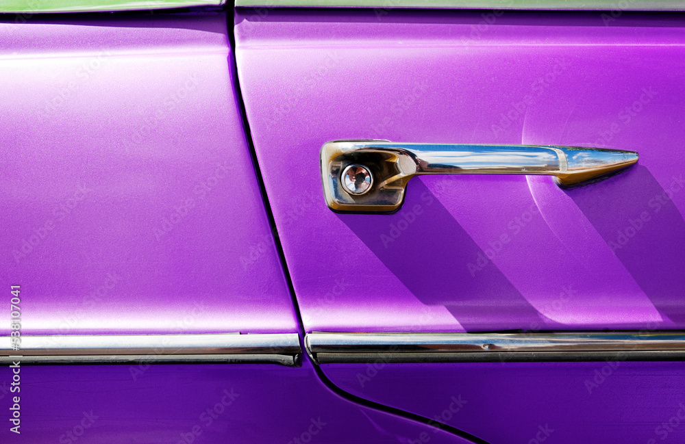 Aficiones automovilísticas y coches clásicos. Detalle de la puerta de un coche de época en tono morado.
