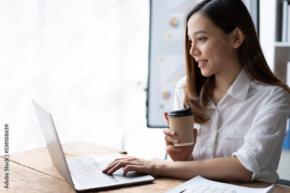 Portrait of an Asian young business Female working on a laptop computer in her workstation.Business people employee freelance online report marketing e-commerce telemarketing concept. Portrait of an Asian young business Female working on a laptop computer in her workstation.Business people employee freelance online report marketing e-commerce telemarketing concept.