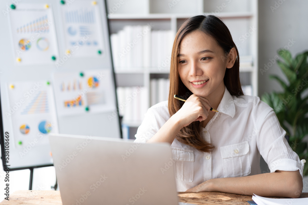 Portrait of an Asian young business Female working on a laptop computer in her workstation.Business people employee freelance online report marketing e-commerce telemarketing concept. Portrait of an Asian young business Female working on a laptop computer in her workstation.Business people employee freelance online report marketing e-commerce telemarketing concept.