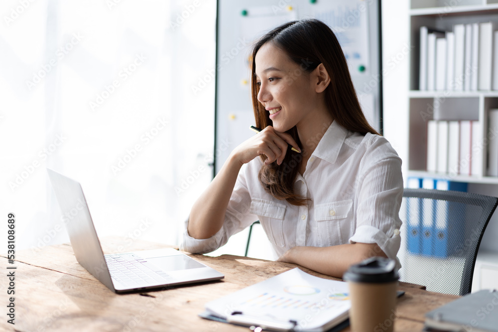 Portrait of an Asian young business Female working on a laptop computer in her workstation.Business people employee freelance online report marketing e-commerce telemarketing concept. Portrait of an Asian young business Female working on a laptop computer in her workstation.Business people employee freelance online report marketing e-commerce telemarketing concept.