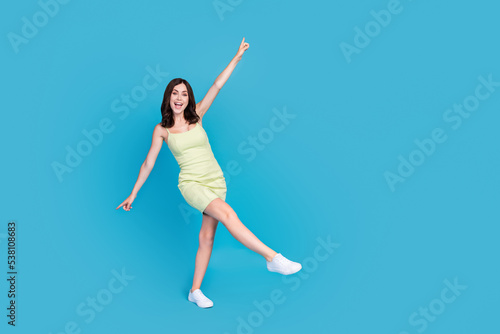 Full size photo of lovely cheerful girl point fingers dancing clubbing isolated on blue color background © deagreez