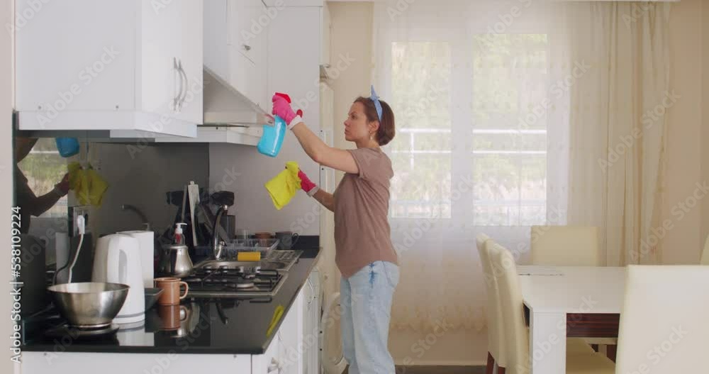 Housewife cleaning the furniture in the kitchen while doing the housework Housewife cleaning the furniture in the kitchen while doing the housework