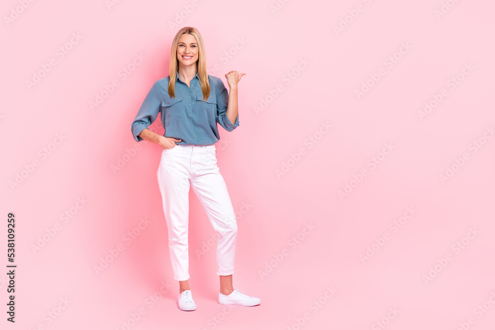 Full length photo of pretty cheerful person indicate thumb finger empty space isolated on pink color background Full length photo of pretty cheerful person indicate thumb finger empty space isolated on pink color background