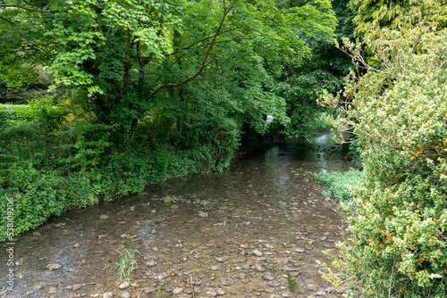 the ambling Bybrook River flowing through Castle Combe in a wooded Cotswold Valley photo