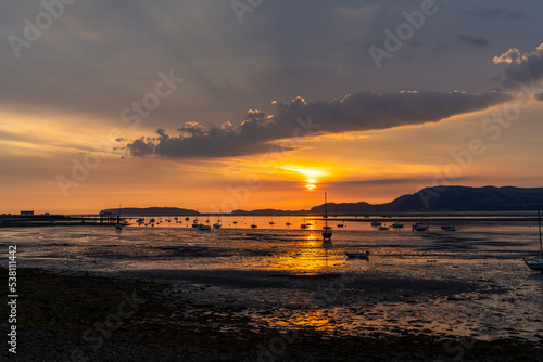 landscape of the Menai Strait with many boats at anchor and the mountains of Snowdonia behind