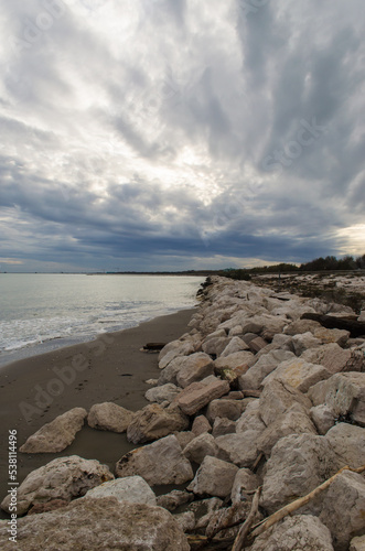 I murazzi, tipici sbarramenti di pietre, sulla spiaggia del Lido di Venezia in una giornata invernale con il cielo pieno di nuvole grigie