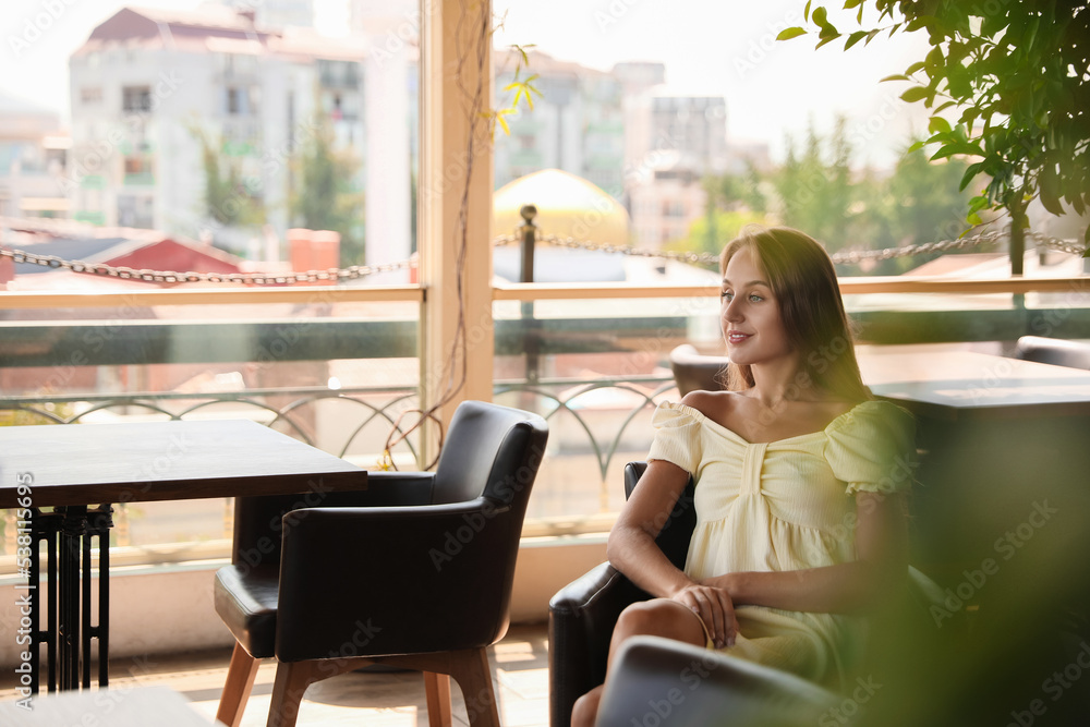 Beautiful young woman sitting on indoor terrace in cafe Beautiful young woman sitting on indoor terrace in cafe