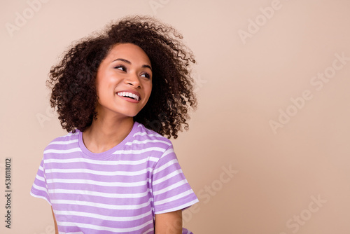 Photo of shiny pretty lady wear violet t-shirt looking empty space smiling isolated beige color background © deagreez