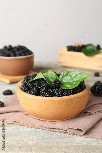 Bowl of delicious ripe black mulberries on wooden table