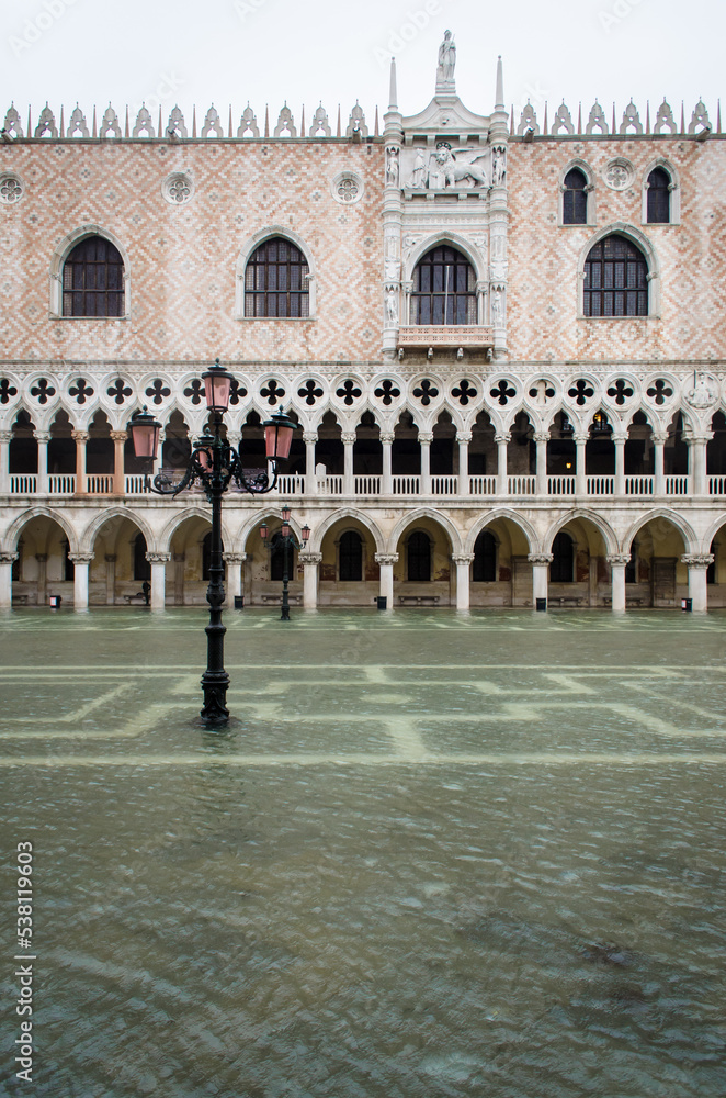 Piazzetta San Marco a Venezia invasa dall'acqua alta con un lampione e la facciata di Palazzo Ducale