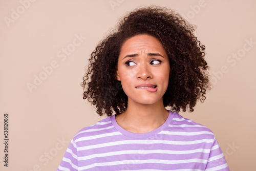 Closeup photo of young attractive pretty woman wear striped t-shirt look empty space nervous bite lips stressed isolated on beige color background © deagreez