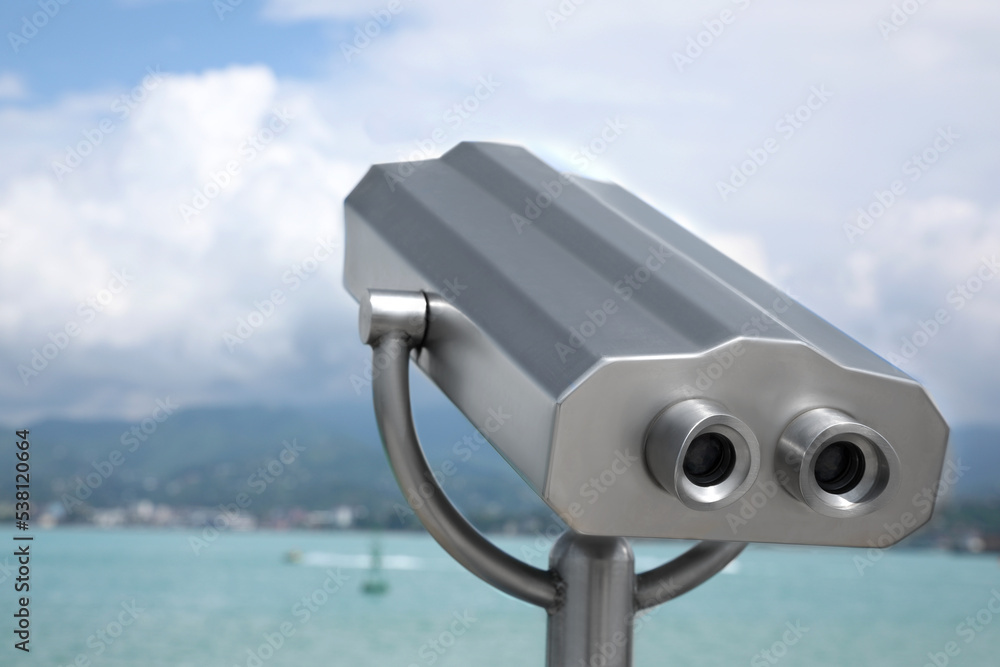 Metal tower viewer installed near sea. Mounted binoculars