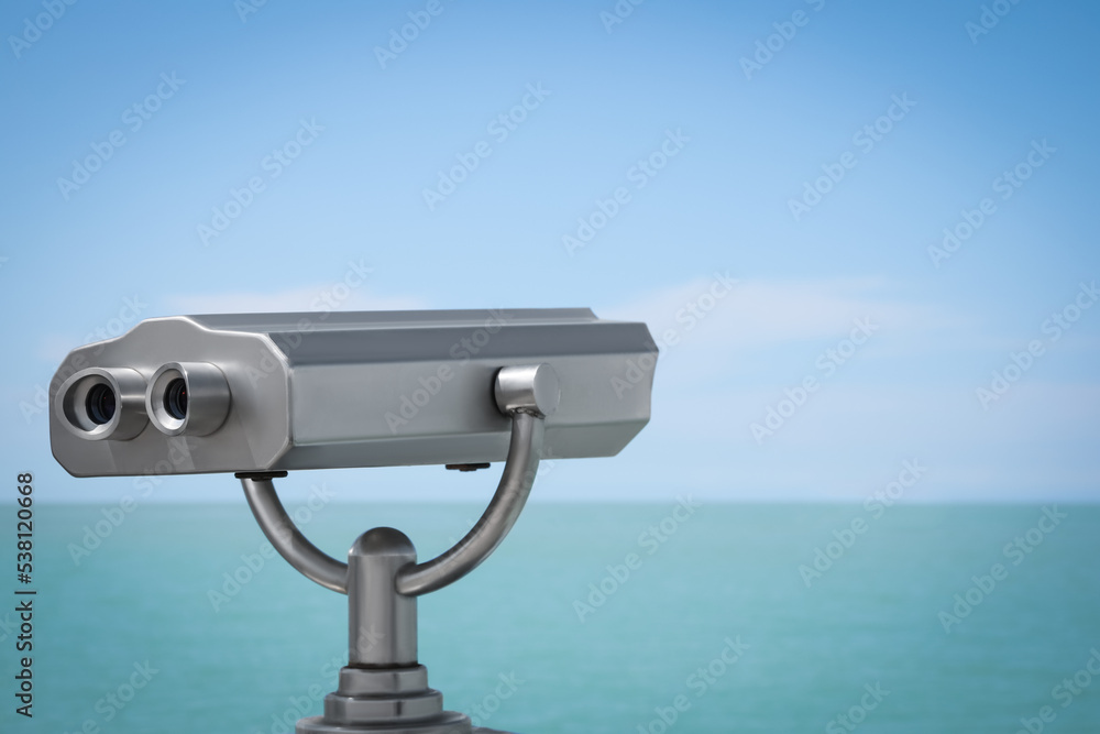 Metal tower viewer installed near sea, space for text. Mounted binoculars