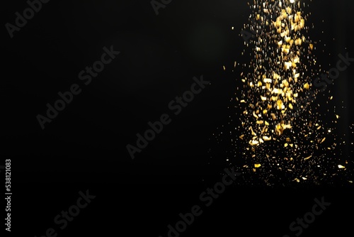 Shiny golden glitter falling down on black background, space for text. Bokeh effect