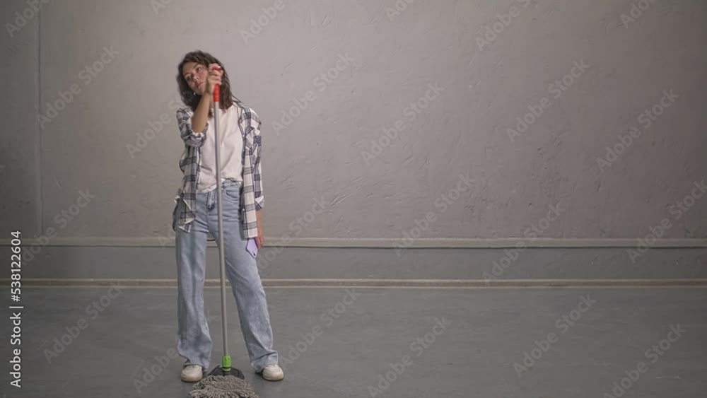 the girl holds a mop and a smartphone and dances. live video the girl holds a mop and a smartphone and dances. live video