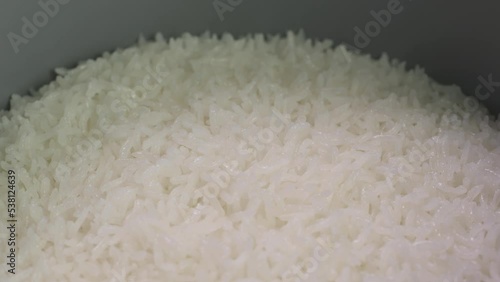 Super close up opening rice cooker lid to show cooked white jasmine Thai long grain rice hot steaming.