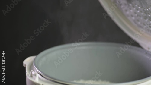 Hand opening rice cooker with steam coming out of cooked rice slow motion.