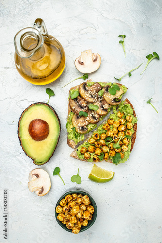 Healthy avocado toasts with chickpeas and mushrooms on a light background, vegetarian vegan food. vertical image. top view. place for text